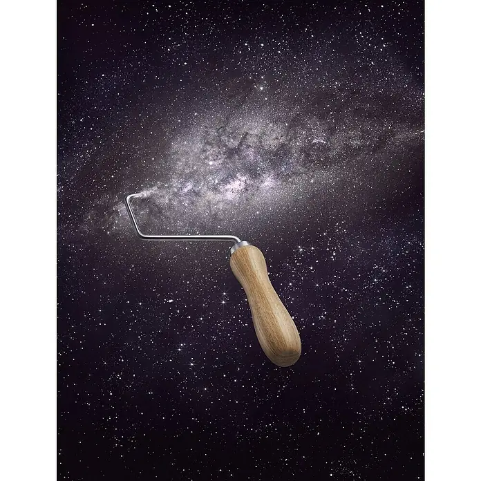 SCHÖNER WOHNEN-Farbe Wandfarbe Trendfarbe - Universe, Matt, 2,5 l, Konservierungsmittelfrei - Ein Farbwagen mit Holzgriff schwebt vor einem Hintergrund aus Sternen und Galaxien, der an das Universum erinnert.