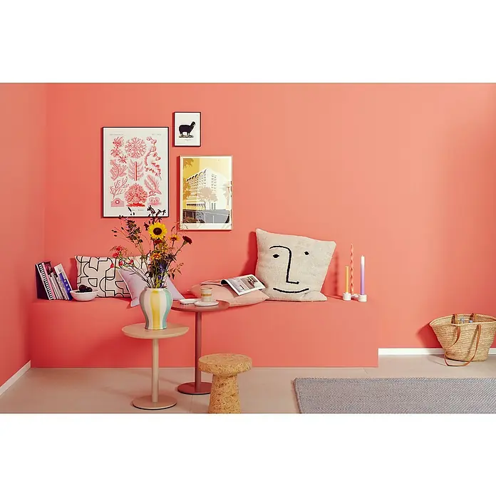 SCHÖNER WOHNEN-Farbe Wandfarbe Trendfarbe Jubiläumsedition - Summer, Matt, 2,5 l, Konservierungsmittelfrei - Wohnzimmer mit korallenroten Wänden, Kunst, Sitzbank mit Kissen, Beistelltischen, Hocker, Teppich und Korb für ein gemütliches Ambiente.