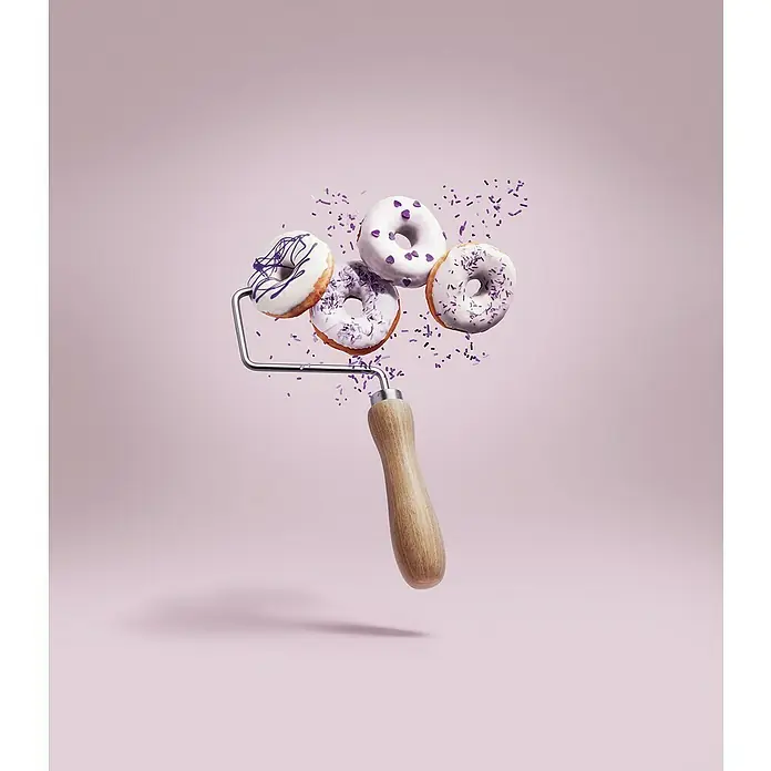 SCHÖNER WOHNEN-Farbe Wandfarbe Trendfarbe - Donut, Matt, 2,5 l, Konservierungsmittelfrei - Das Bild zeigt vier köstliche Donuts auf einer Farbwalze, dekoriert mit lila Streuseln, vor einem zartrosa Hintergrund.