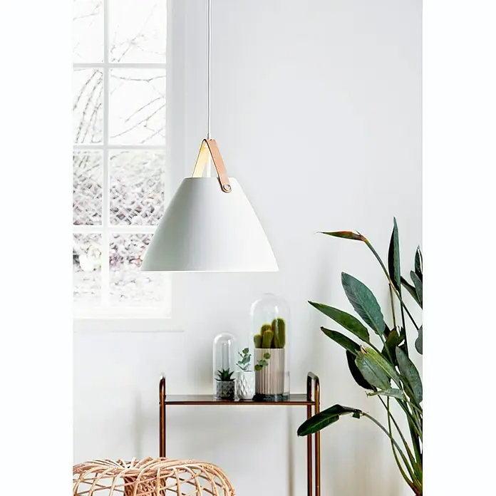 Nordlux Strap Lámpara colgante redonda - 60 W, Ø x Al: 36 x 37 cm, Blanco, E27 - Una lámpara colgante blanca y moderna con una correa de cuero que emite un brillo cálido, colgando sobre una estantería con suculentas.