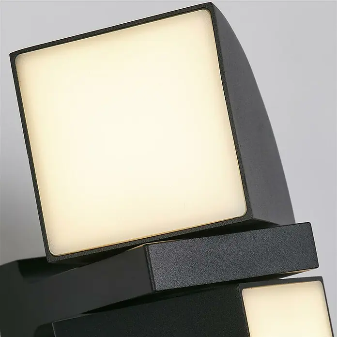 Searchlight LED-Außenwandleuchte Dakota - 8 W, 12 x 12 x 20,5 cm, Schwarz, IP44 - Nahaufnahme einer modernen, schwarzen LED-Wandleuchte mit quadratischen, leuchtenden Elementen, die ein warmes Licht ausstrahlen.