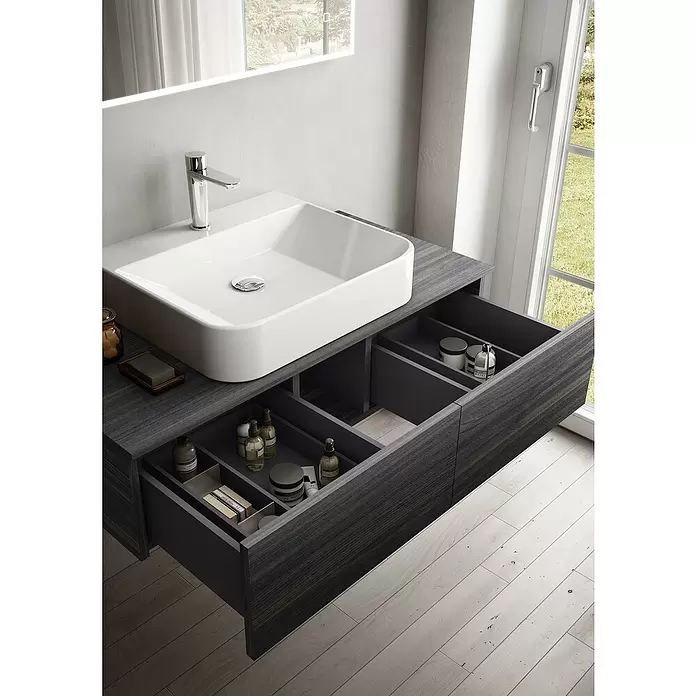 Riva Draw Waschtischunterschrank - 100 x 50 x 25 cm - Moderner Waschtisch aus dunklem Holz mit weißem Becken und geöffneten Schubladen, die organisierte Aufbewahrung für Toilettenartikel zeigen. In einem hellen Bad.