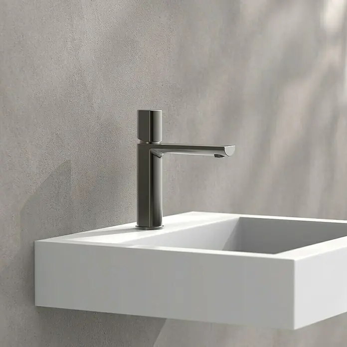 Camargue Waschtischarmatur Madrid - Graphit, Matt - Ein stilvoller, matter, dunkler Wasserhahn auf einem modernen, minimalistischen, weißen Waschbecken vor einer grauen Wand.