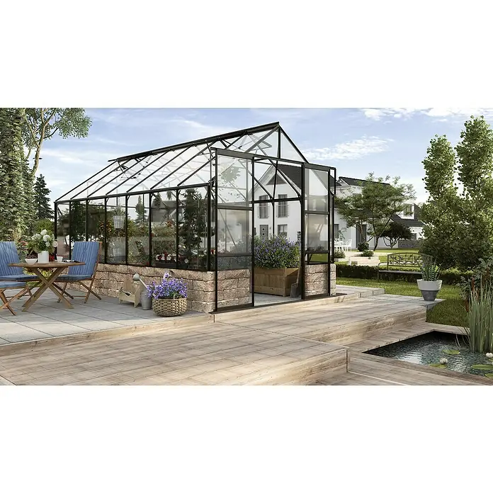 Vitavia Gewächshaus Cassandra 11500 Plus - Außenmaß inkl. Dachüberstand (B x T): 257 x 448 cm, 3 mm, Schwarz - Das Bild zeigt ein Gewächshaus mit Glaswänden und einem schwarzen Rahmen in einem Garten. Es gibt auch einen Teich, Blumen und Gartenmöbel zu sehen.