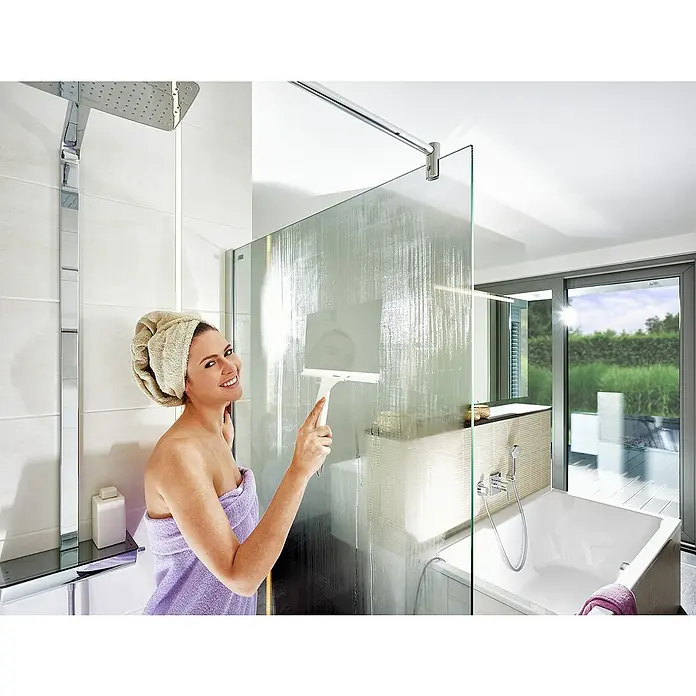 Leifheit Bad-& Duschabzieher Cabino Showerslider - Weiß, Kunststoff - Eine Frau putzt eine Duschwand mit einem Abzieher in einem modernen Badezimmer, das die hochwertige Badarmatur hervorhebt.