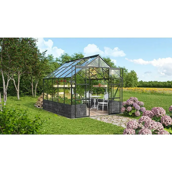 Vitavia Gewächshaus Cassandra 8300 - Außenmaß inkl. Dachüberstand (B x T): 257 x 323 cm, 3 mm, Schwarz/ Basalt - Dieses Bild zeigt ein Gewächshaus im Freien mit Pflanzen und einem Tisch mit Stühlen darin, umgeben von Blumen.