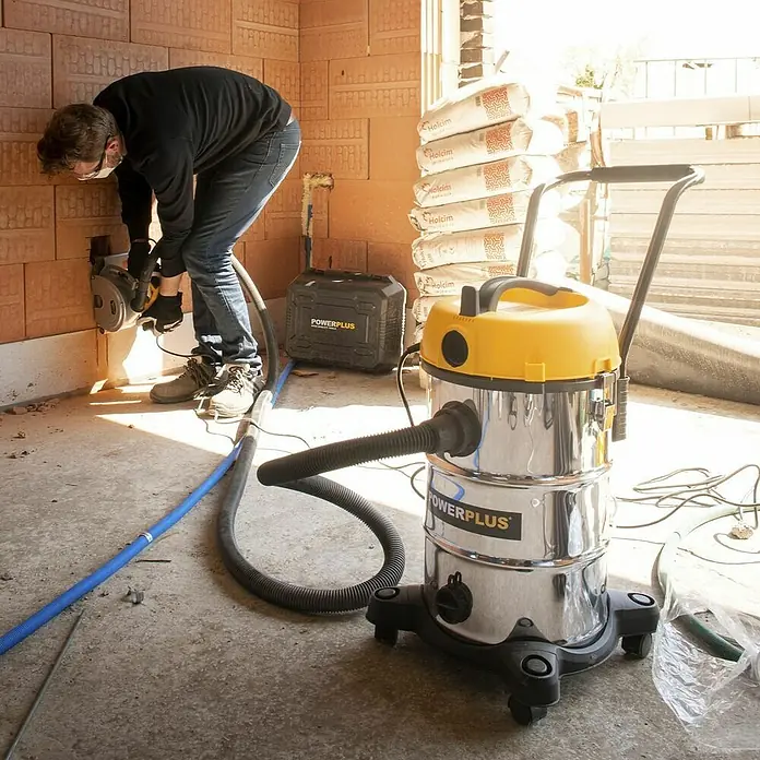 PowerPlus Aspirador en seco y húmedo eléctrico POWX3240 - 1.200 W, Volumen de recipiente: 30 l, Con bolsa - Aspiradora en seco y húmedo POWERPLUS en uso en una obra durante trabajos de construcción con una rozadora.