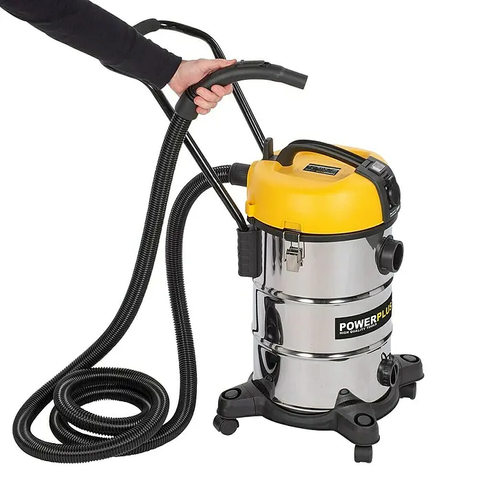 PowerPlus Aspirador en seco y húmedo eléctrico POWX3240 - 1.200 W, Volumen de recipiente: 30 l, Con bolsa - Una aspiradora Powerplus amarilla y plateada con manguera y asa sostenida por una persona, sobre un fondo negro.
