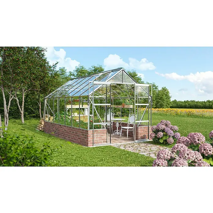 Vitavia Gewächshaus Cassandra 11500 Plus - Außenmaß inkl. Dachüberstand (B x T): 257 x 448 cm, 3 mm, Aluminium - Nahaufnahme eines Gewächshauses mit einem Tisch und Stühlen im Inneren, umgeben von üppigem Grün.
