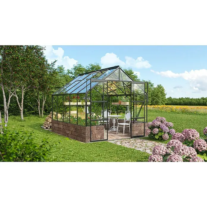 Vitavia Gewächshaus Cassandra 8300 - Außenmaß inkl. Dachüberstand (B x T): 257 x 323 cm, 3 mm, Schwarz/ Herbstlaub - Ein geräumiges Gewächshaus mit einem Tisch und Stühlen darin, umgeben von Blumen und Bäumen, lädt zum Verweilen ein.