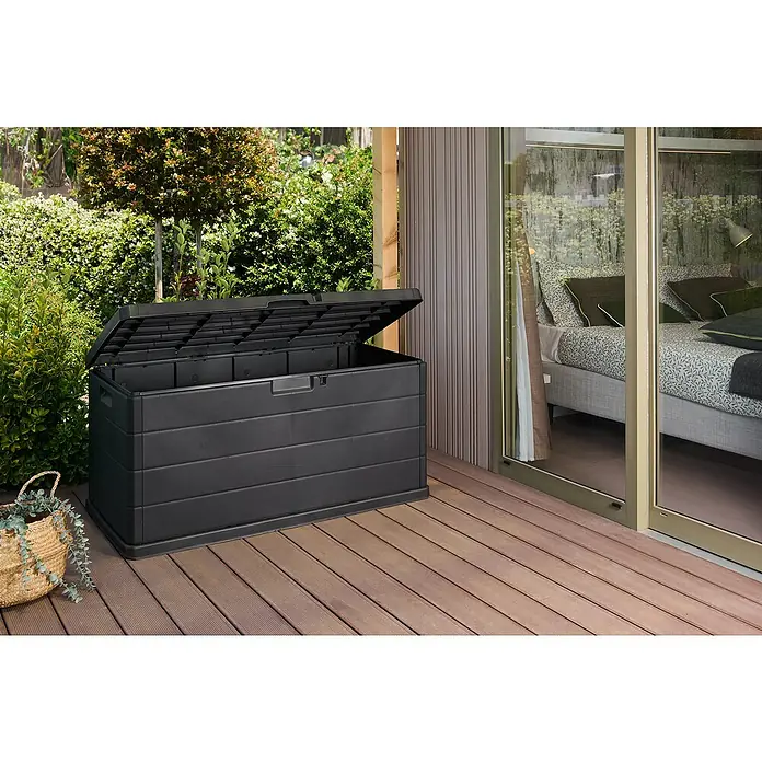 Progarden Garten-Aufbewahrungsbox Alpha - L x B x H: 118 x 59 x 57 cm, Kunststoff, Anthrazit - Ein geräumiger, geöffneter, schwarzer Gartentruhe aus Kunststoff steht auf einer Holzterrasse neben einem Haus mit Schiebetüren.