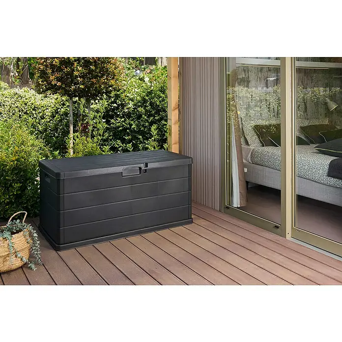 Progarden Garten-Aufbewahrungsbox Alpha - L x B x H: 118 x 59 x 57 cm, Kunststoff, Anthrazit - Eine schwarze Gartenbox steht auf einer hölzernen Terrasse, neben einer Glas-Schiebetür und üppigem Grün. Ideale Aufbewahrung für den Außenbereich.