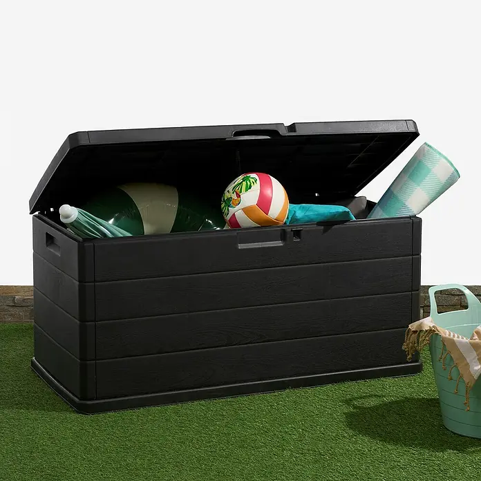 Progarden Garten-Aufbewahrungsbox Alpha - L x B x H: 118 x 59 x 57 cm, Kunststoff, Anthrazit - Eine geöffnete schwarze Gartenbox gefüllt mit Strandspielzeug und einer Decke auf grünem Rasen. Praktische Aufbewahrung für den Außenbereich.