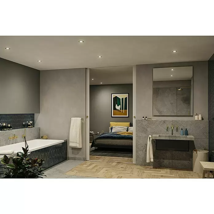 Paulmann Nova LED-Einbauleuchte rund Plus - 6,5 W, Ø x H: 9,3 x 4,5 cm, Gold - Modernes Badezimmer mit Badewanne, Steinwaschbecken und Messingarmaturen, verbunden mit einem Schlafzimmer. Dunkle Fliesen und Sichtbetonwände.