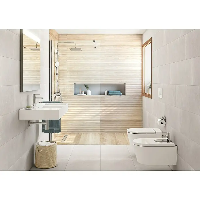 Revestimiento de pared Weekend - 30 x 90 cm, Gris, Mate, Rectificado - La imagen muestra un baño moderno con un mueble de lavabo blanco, inodoro y bidé. Azulejos claros y detalles de madera crean un ambiente elegante.