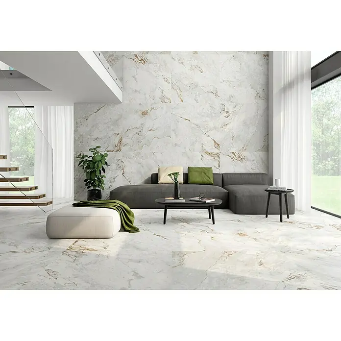 BHS Showroom Pavimento porcelánico Mármore Paraná - 90 x 90 cm, Blanco, Mate, Rectificado - Un salón luminoso con baldosas de mármol de gran formato que cubren paredes y suelo. Decoración moderna con sofá gris y plantas.