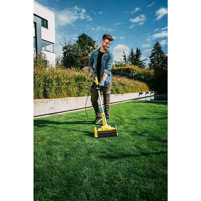 Gloria Bodenreinigungsbürste Multibrush XL - 500 W, Arbeitsbreite: 32 cm, Höhenverstellung: 115 cm - 135 cm - Ein Mann benutzt einen gelben Rasenlüfter im Garten. Das Gerät hilft, den Rasen gesund und gepflegt zu halten.
