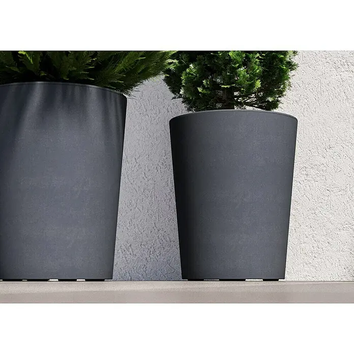 Deroma Millennium Pflanzkübel rund - Außenmaß (Ø x H): 43,5 x 53,5 cm, Aus recyceltem Kunststoff, Ashgrey - Nahaufnahme von zwei grauen Pflanzgefäßen mit grünen Pflanzen auf einer ebenen Fläche vor einer Wand.