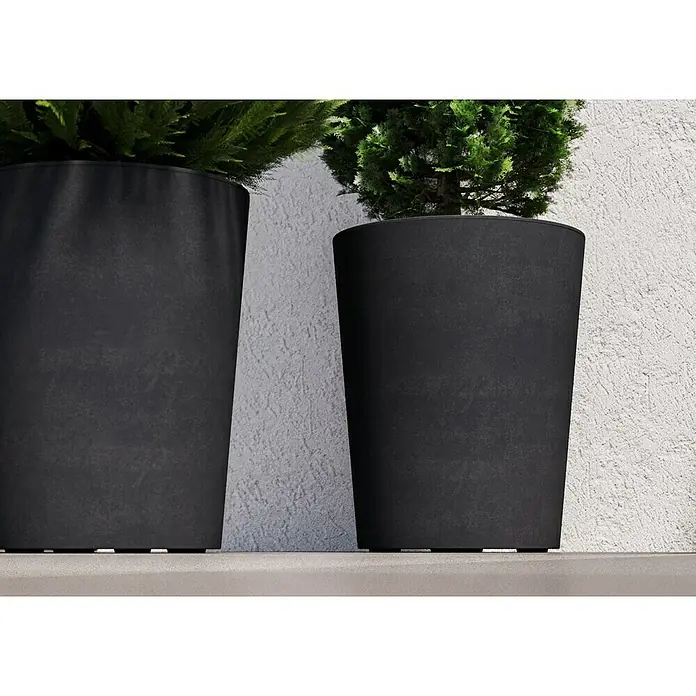 Deroma Millennium Pflanzkübel rund - Außenmaß (Ø x H): 43,5 x 53,5 cm, Aus recyceltem Kunststoff, Anthrazit - Zwei moderne, schwarze Pflanzgefäße mit grünen Pflanzen vor einer strukturierten Wand. Sie bieten eine stilvolle Ergänzung für jeden Raum.