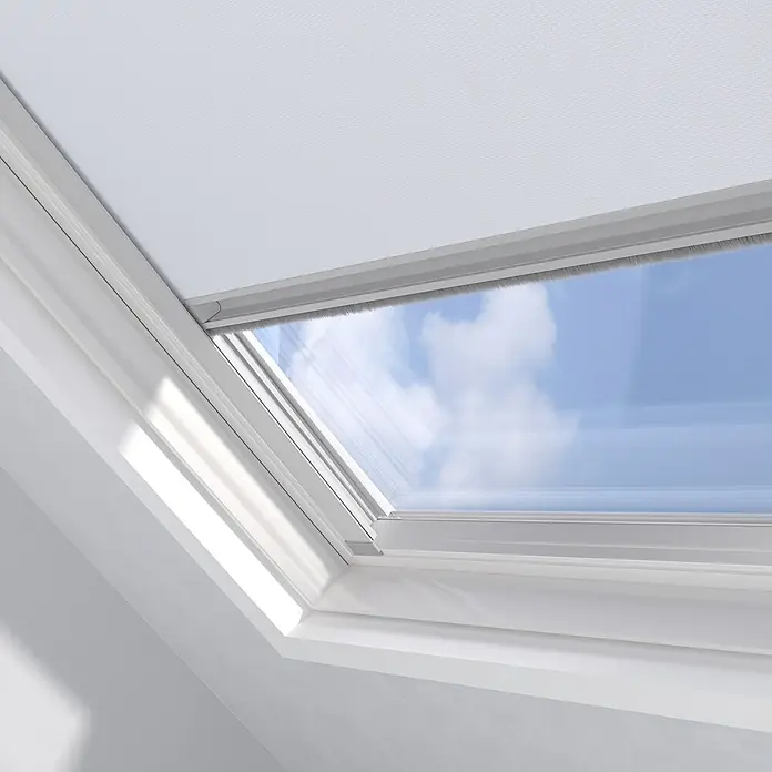 Dachfensterrollo Sky UK08 - Weiß, Manuell - Nahaufnahme eines VELUX Dachfensters mit Blick auf den blauen Himmel, das Tageslicht hereinlässt und eine helle Atmosphäre schafft.
