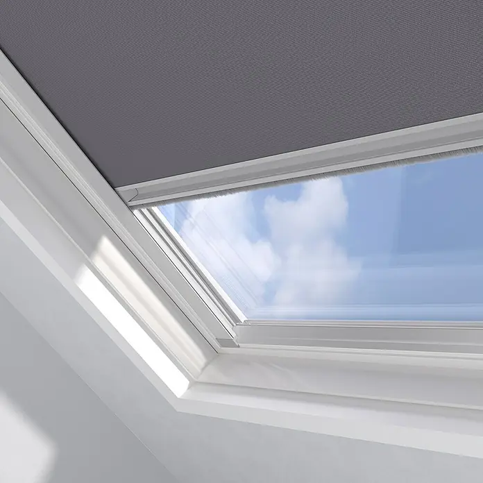 Dachfensterrollo Sky UK08 - Grau, Manuell - Detailaufnahme eines Dachfensters mit Rollo in Grau, das teilweise geöffnet ist und den Blick auf den blauen Himmel freigibt.