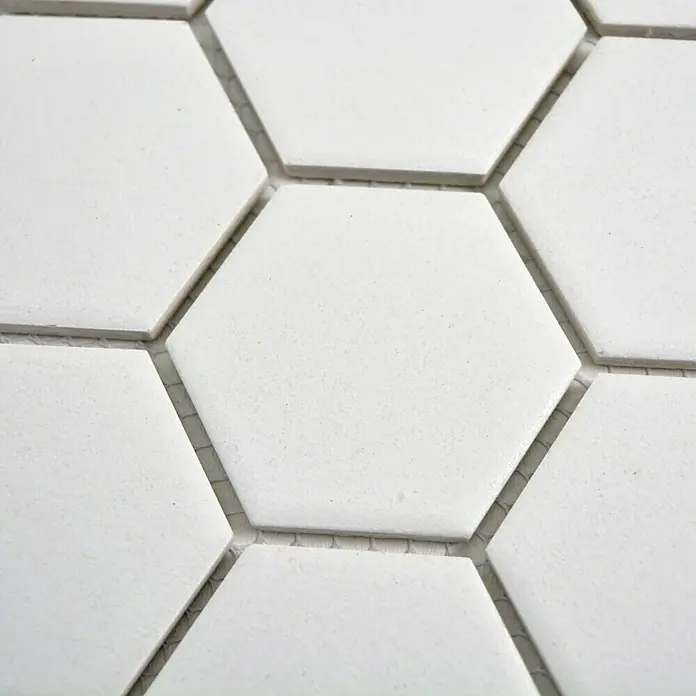 Mosaikfliese Hexagon Uni CU HX101 - 32,5 x 28,1 cm, Weiß, Matt - Nahaufnahme von weißen sechseckigen Fliesen mit Fugenmörtel, ideal für Küchen- oder Badprojekte.