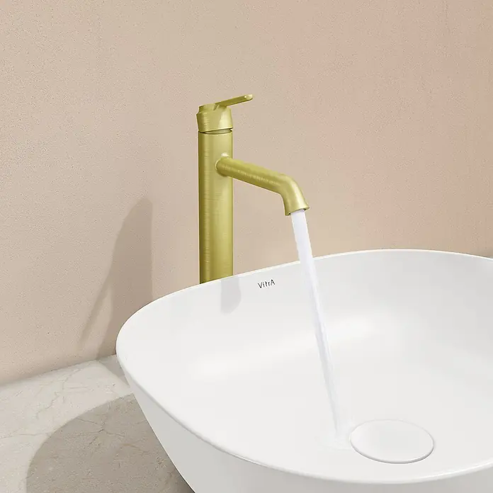 VitrA Plural Aufsatzwaschbecken - 45 x 38 cm, Mit schmutzabweisender Glasur, Hahnloch: Ohne, Ohne Überlauf, Weiß - Nahaufnahme eines modernen goldenen Wasserhahns von Vitra über einem weißen Waschbecken, Wasser läuft.