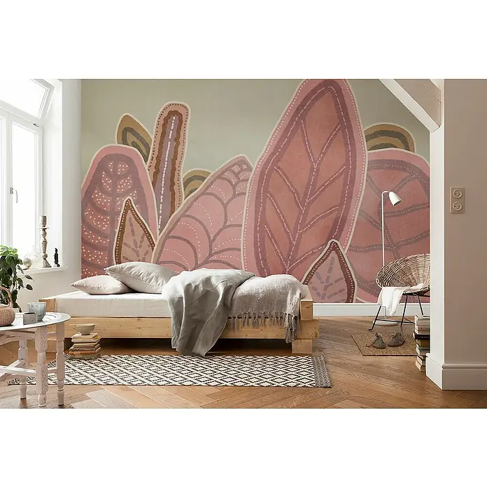 Komar Flair Fototapete Papunya Leafs - B x H: 350 x 250 cm, Vlies - Schlafzimmer mit einem hellen Holzbett mit Überwurf, einem gemusterten Teppich und einer Wand mit Blattmotiven.