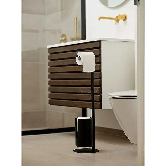 Zone Denmark WC-Bürstengarnitur RIM - ABS-Kunststoff, Black, 20 cm - Elegante Badezimmeraufnahme mit einem freistehenden Toilettenpapierhalter in Schwarz, der stilvoll neben einer modernen Toilette platziert ist.