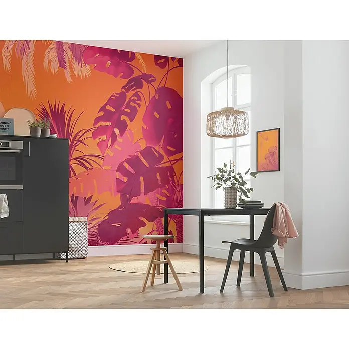 Komar Flair Fototapete Funky Jungle - B x H: 250 x 250 cm, Vlies - Ein Essbereich mit Esstisch und Stuhl, beleuchtet durch eine Pendelleuchte, vor einer Wand mit einem auffälligen, tropischen Muster.