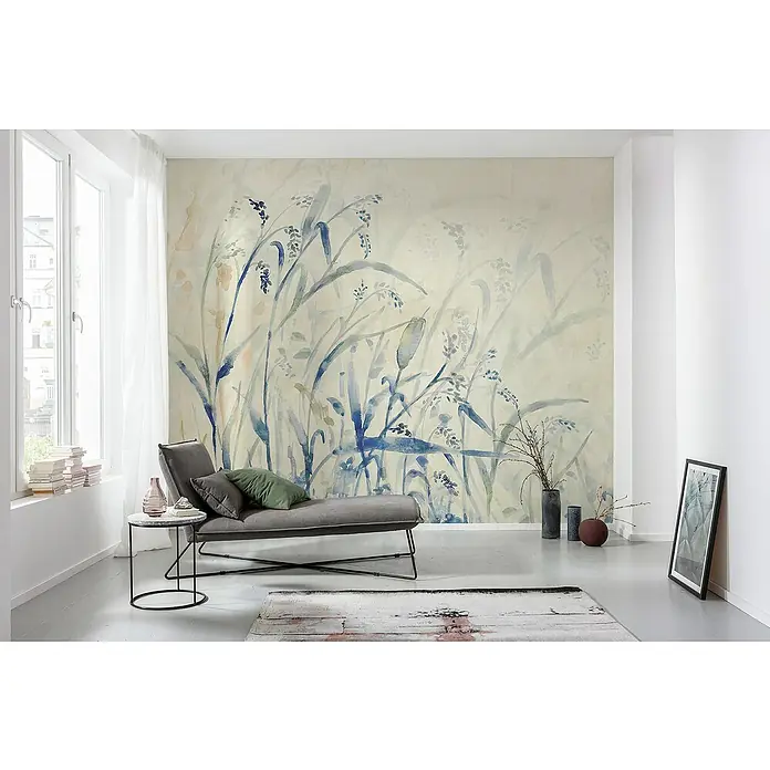 Komar Flair Fototapete Aquarel-Field - B x H: 300 x 250 cm, Vlies - Ein stilvolles Wohnzimmer mit einer floralen Tapete, einem grauen Sofa und einem runden Beistelltisch, die eine entspannende Atmosphäre schaffen.
