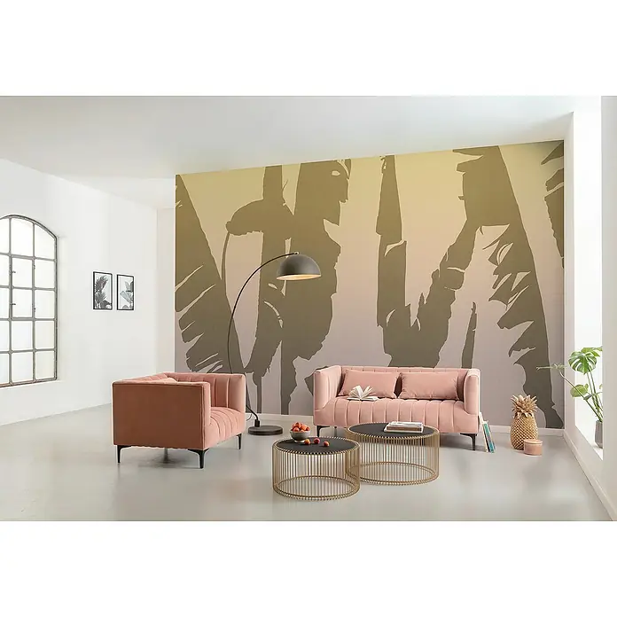 Komar Flair Fototapete Bahama Bananas - B x H: 350 x 250 cm, Vlies - Wohnzimmer mit modernem rosa Sofa und Sessel, stilvollen goldenen Tischen und einer eleganten Stehlampe vor einer Dschungeltapete.