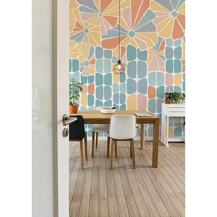 Komar Flair Fototapete Garden Dream - B x H: 300 x 250 cm, Vlies - Esszimmer mit Holztisch und Stühlen vor einer Wand mit Blumenmuster-Tapete, ergänzt durch eine elegante Hängelampe und einen hellen Holzboden.