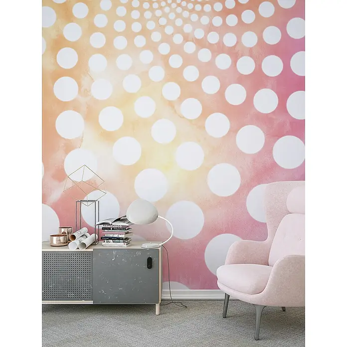 Komar Flair Fototapete Fibonacci Sunset - B x H: 250 x 250 cm, Vlies - Modernes Interieur mit pastellfarbenem Sessel und einem Sideboard, das Bücher und Dekorationen trägt, vor einer Wand mit einem Punktmuster.