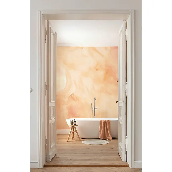 Komar Flair Fototapete Candy Peach - B x H: 400 x 250 cm, Vlies - Freistehende Badewanne mit Handtuch und kleinem Hocker im Badezimmer mit abstrakter Wandgestaltung, gesehen durch offene, weiße Flügeltüren.