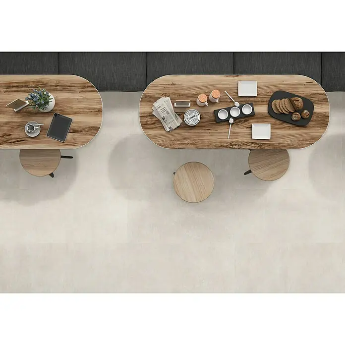 Pavimento porcelánico Logan - 60 x 60 cm, Arena, Mate, Rectificado - Vista superior de dos mesas de madera con sillas redondas, ideal para una cafetería u oficina elegante.