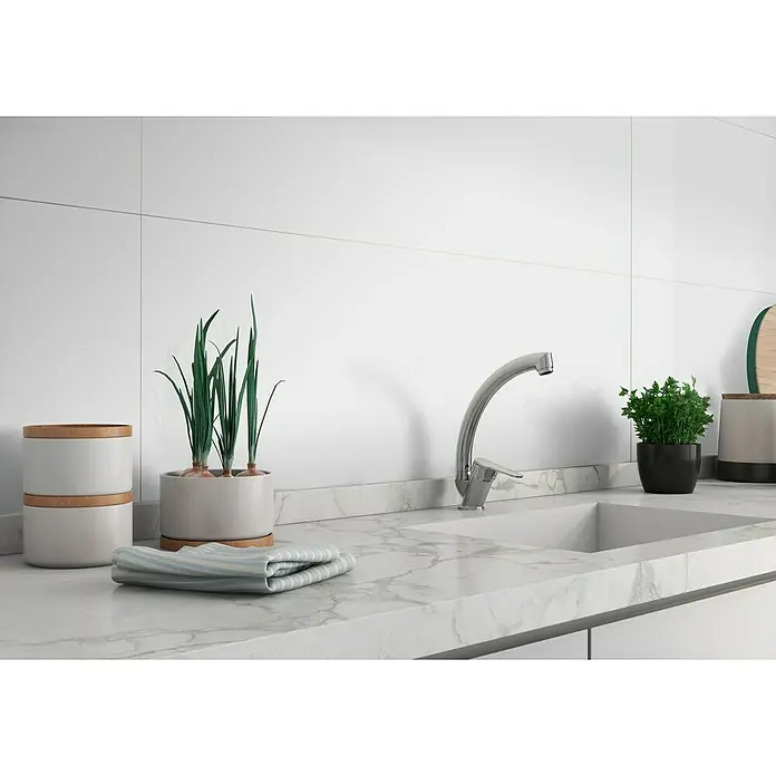 Revestimiento de pared Montreal - 30 x 90 cm, Blanco, Mate, Rectificado - Una moderna escena de cocina con un elegante grifo, hierbas frescas y recipientes elegantes en una encimera de mármol.