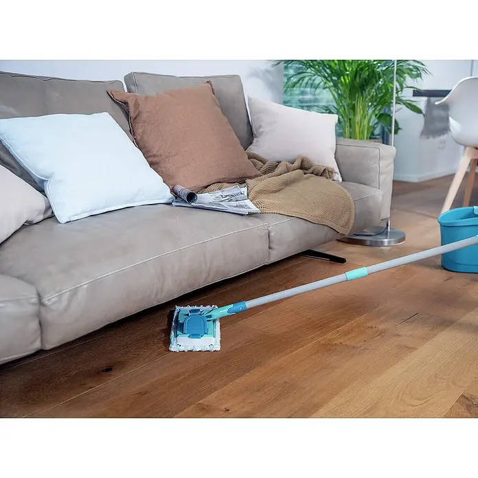 Leifheit Bodenwisch-Set Power Clean + Gratis Micro Duo - 4 -tlg. - Das Bild zeigt einen Bodenwischer im Einsatz auf einem Holzboden vor einem bequemen Sofa, was die einfache Reinigungslösung hervorhebt.
