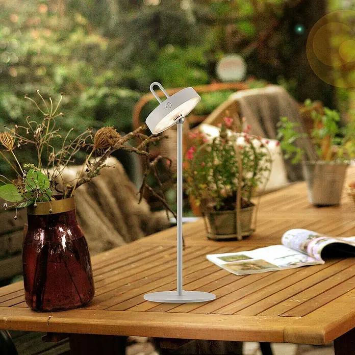 Paul Neuhaus Lámpara de sobremesa LED Amag - 1,5 W, L x An x Al: 15 x 15 x 47,2 cm, Gris, Blanco cálido - Lámpara de mesa de metal sobre una mesa de madera con plantas y una revista al fondo.
