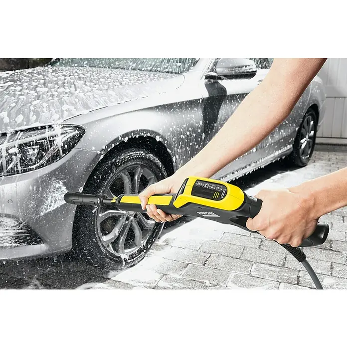 Kärcher Hochdruckreiniger K 5 Power Control Flex - 145 bar, 2.100 W, Fördermenge: 500 l/h, Ohne Home Kit - Eine Person benutzt einen Kärcher Hochdruckreiniger, um ein Auto mit Schaum zu reinigen. Das Gerät ist gelb und schwarz.