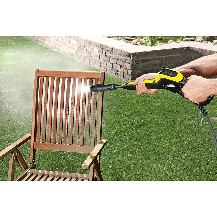 Kärcher Hochdruckreiniger K 4 Power Control Flex Home - 130 bar, 1.800 W, Fördermenge: 420 l/h, Mit Home Kit - Ein Mann reinigt einen hölzernen Gartenstuhl mit einem Kärcher Hochdruckreiniger, um Schmutz und Ablagerungen zu entfernen.
