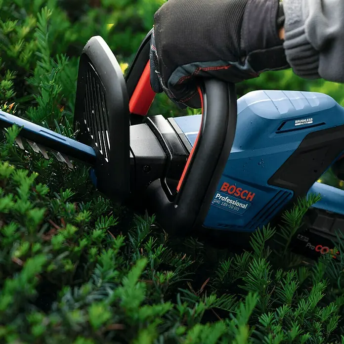 Bosch Professional AMPShare 18V Akku-Heckenschere GHE 18V-50 II - 18 V, Ohne Akku, Schwertlänge: 50 cm - Nahaufnahme einer blauen Bosch Akku-Heckenschere Professional GHE 18V-50 II in Aktion, gehalten von einer behandschuhten Hand.