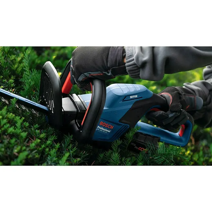 Bosch Professional AMPShare 18V Akku-Heckenschere GHE 18V-60 II - 18 V, Ohne Akku, Schwertlänge: 60 cm - Eine Bosch Professional Akku-Heckenschere GHE 18V-60, die von einer Person mit Gartenhandschuhen bedient wird, schneidet eine grüne Hecke.