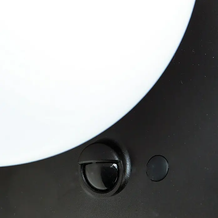 Arte confort Aplique solar para exterior Clario - L x An x Al: 13 x 15,2 x 13,7 cm - Primer plano de una lámpara negra para exteriores con sensor de movimiento y una superficie de luz redonda y blanca para el jardín o la terraza.