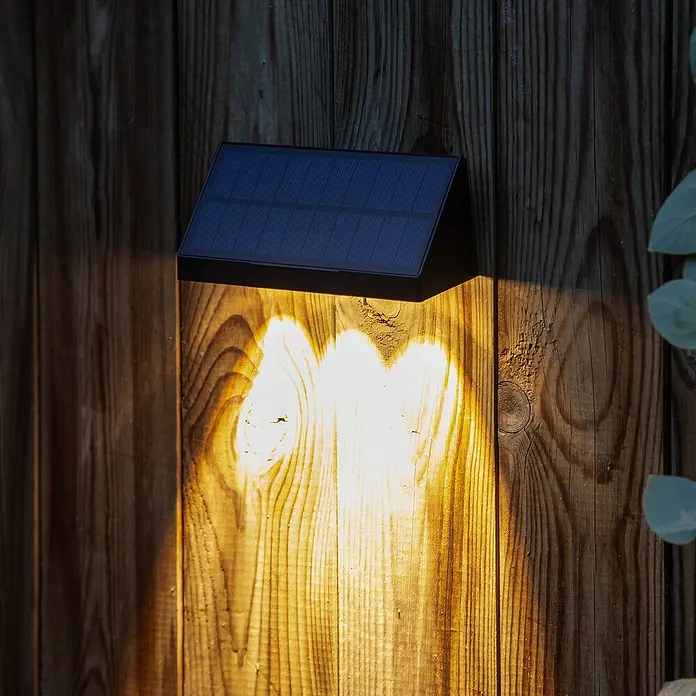 Arte confort Aplique solar para exterior Rigel pack x2 - L x An x Al: 14,5 x 5,1 x 5,8 cm - Lámpara de pared solar que proyecta una luz cálida sobre una pared de madera. La lámpara es compacta y ecológica.