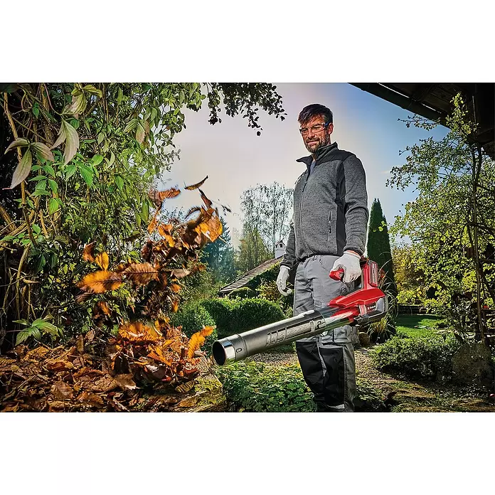 Einhell Professional Akku-Laubbläser GP-LB 18/200LI E - 18 V, Ohne Akku, Blasgeschwindigkeit: 200 km/h, Blasleistung: 670 m³/h - Mann im Garten nutzt roten und schwarzen Laubbläser, um Herbstlaub zu entfernen.