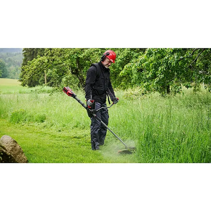Einhell Professional Akku-Motorsense SOLO GP-BC 36/430 LI BL - 36 V, Ohne Akku, Schnittbreite Faden: 43 cm, Schnittbreite Messer: 25,5 cm - Ein Mann mäht Gras mit einem Einhell Akku-Rasentrimmer. Der Rasentrimmer ist rot und schwarz und wird mit einem Akku betrieben.