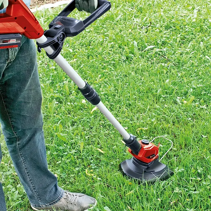 Einhell Power X-Change 18V Akku-Rasentrimmer GE-CT 18 Li - 18 V, 2,5 Ah, Li-Ionen, 1 Akku, Schnittbreite Messer: 24 cm - Eine Person bedient einen Rasentrimmer von Einhell mit rotem Akku auf einer grünen Wiese, um den Rasen zu trimmen.