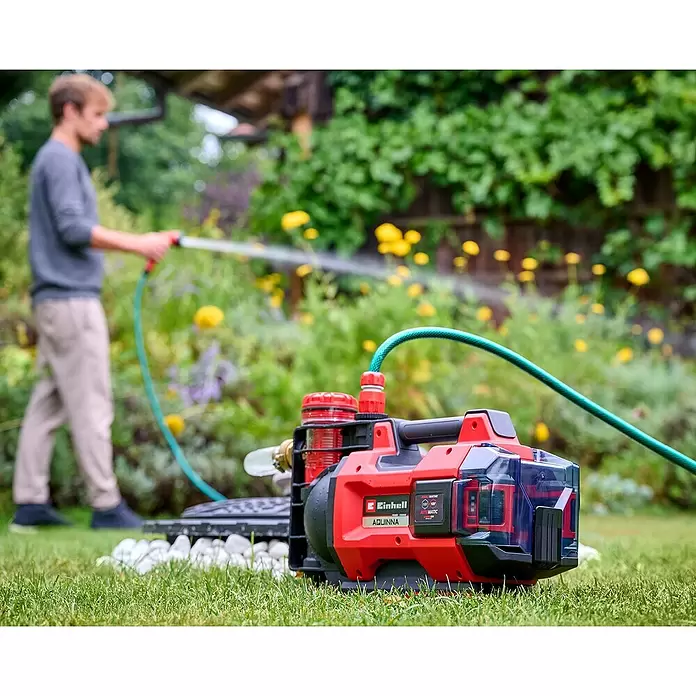 Einhell PXC 18V Akku-Gartenpumpe Aqinna 18/30 F LED Automatic - 18 V, Li-Ionen, Ohne Akku, Max. Fördermenge: 3.000 l/h - Rot-schwarze Einhell Aquinna Akku-Pumpe mit Schlauch, zum Gießen verwendet.