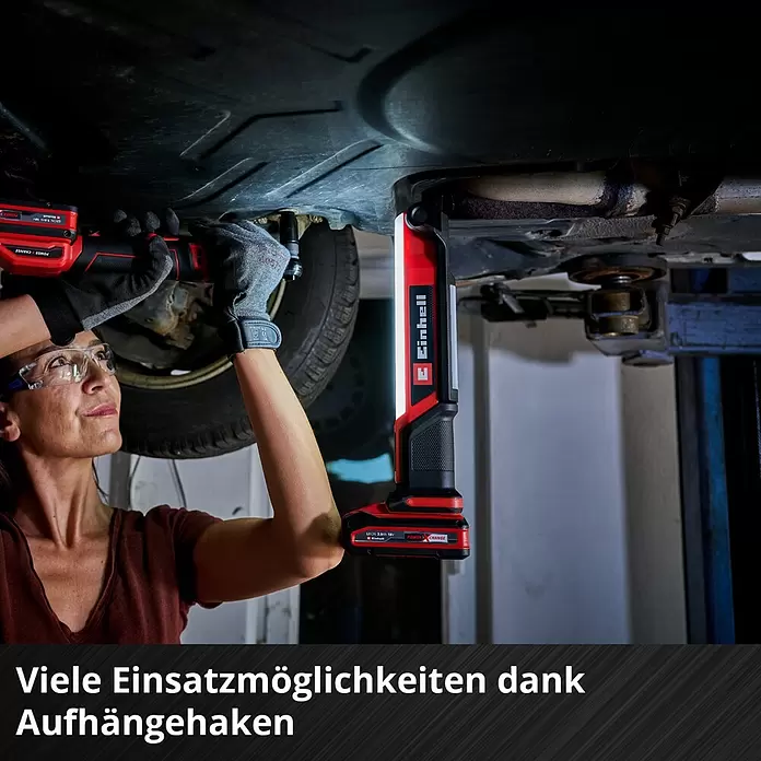 Einhell Power X-Change 18V Akku-Bauleuchte TE-CL 18/1000 S Li - Solo - 18 V, Ohne Akku, Lichtstrom: 1.000 lm - Eine Frau arbeitet unter einem Auto mit einem Einhell Akku-Ratschenschrauber und einer Einhell LED-Arbeitsleuchte, die praktisch am Haken hängt.